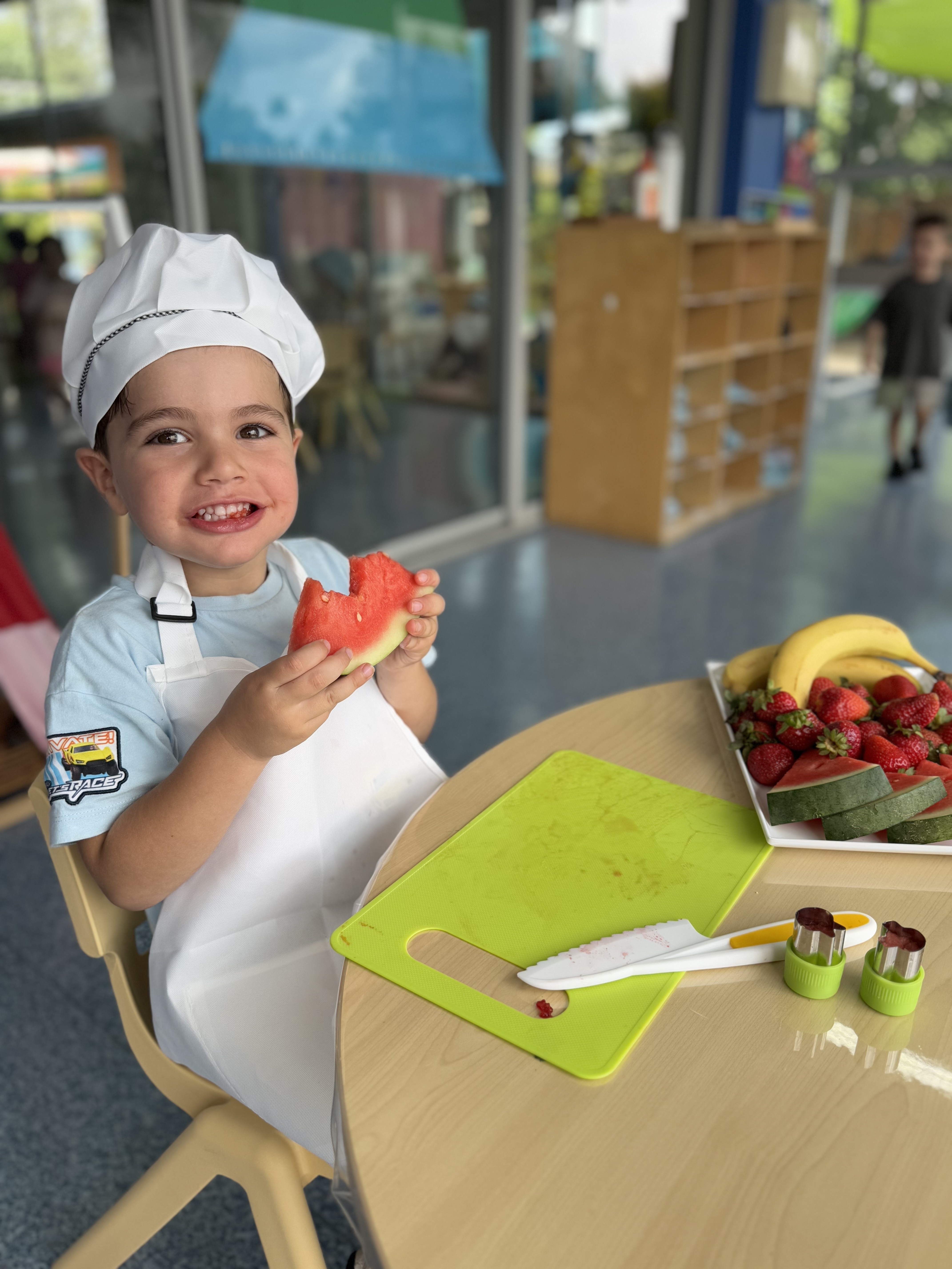 Smiling child taking a big bite of watermelon, enjoying a fresh snack.